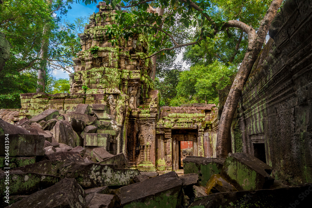 Discover the ancient west gate of Cambodia's Ta Prohm temple (Rajavihara) from a different angle, behind the big collapsed stones in the shadow of the jungle. Discover the ancient west gate of Cambodia's Ta Prohm temple (Rajavihara) from a different angle, behind the big collapsed stones in the shadow of the jungle.