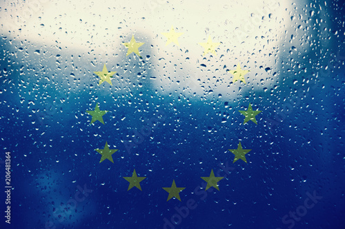 Texture of the European Union flag on the glass with drops of rain light.