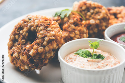 Sabudana vada or Sago fried cake served with peanut chutney over moody background, popular fasting recipe from India.  photo