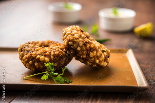 Sabudana vada or Sago fried cake served with peanut chutney over moody background, popular fasting recipe from India.  photo