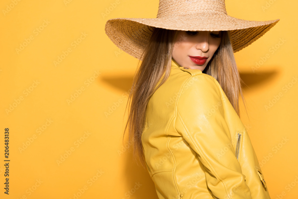 attractive asian female model in straw hat posing on yellow background