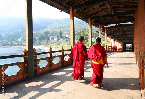 Two young monks walking on  PUNA MOCCHU BAZAM : Antique  wooden bridge at Punakha Dzong Monastery or Pungthang Dewachen Phodrang  Bhutan photo