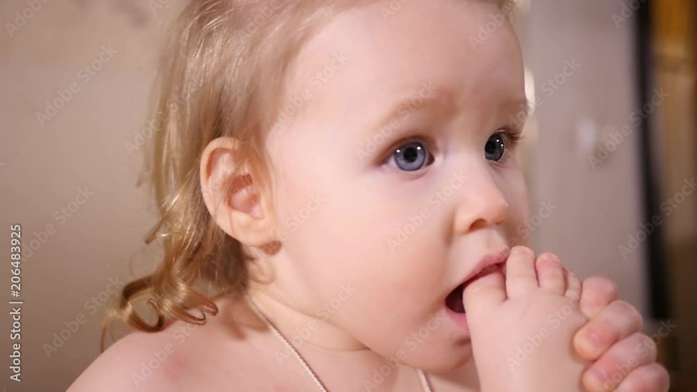 Little baby girl portrait play with her leg sucking biting foot toe putting it in mouth Little baby girl portrait play with her leg sucking biting foot toe putting it in mouth