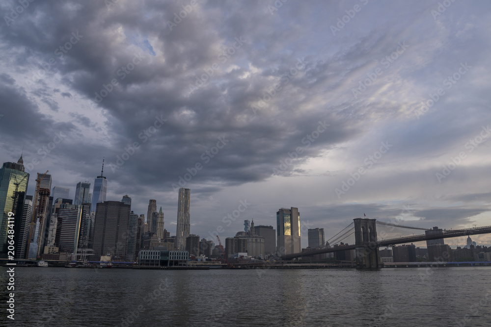 Amazing clouds over New York City skyline and Brooklyn Bridge on Hudson river 