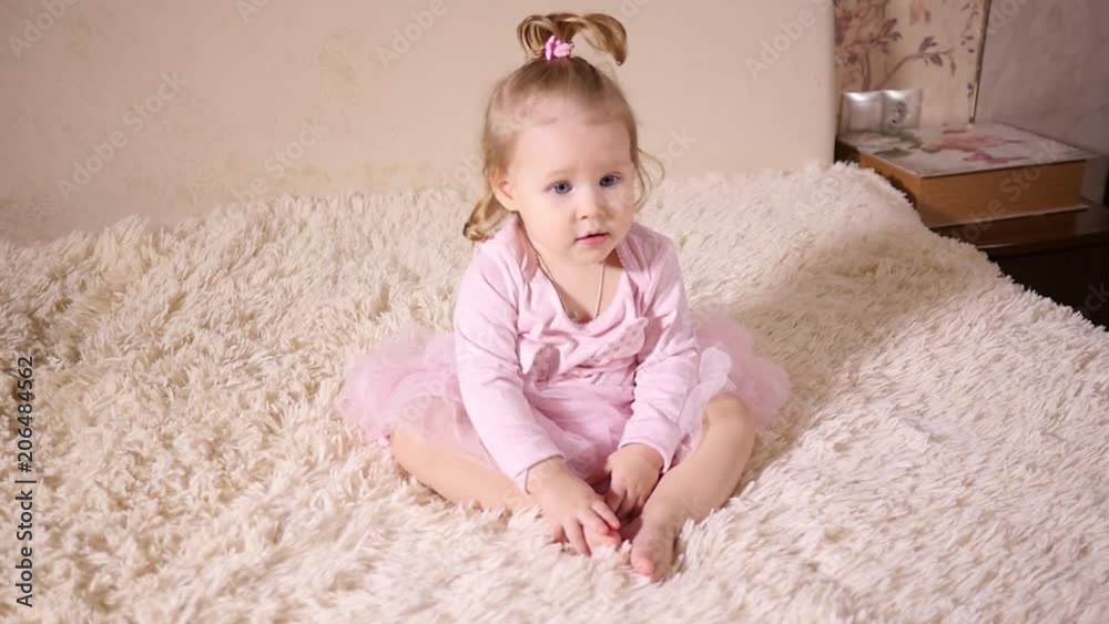 Little baby girl toddler sitting on a bed at home Little baby girl toddler sitting on a bed at home