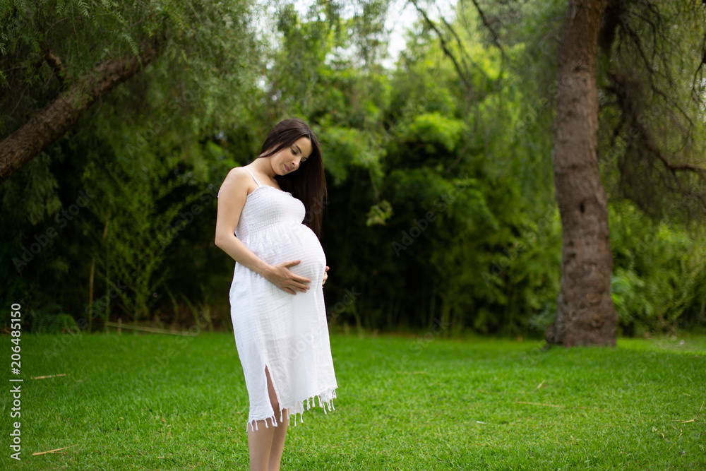 Pregnant couple walks in the park together holding hands Pregnant couple walks in the park together holding hands