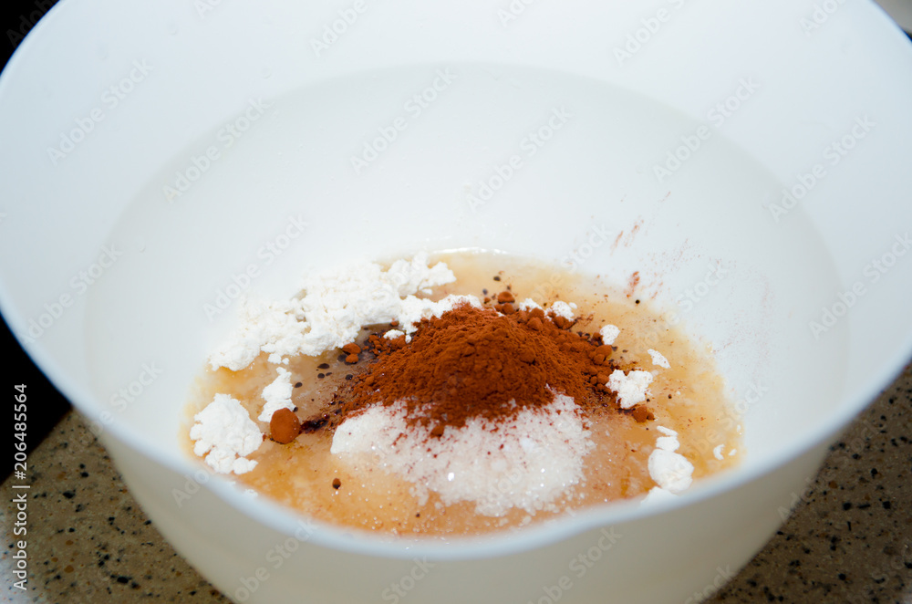 Ingredients mixed for cake, flour, cocoa and sugar are poured into a bowl to prepare cupcakes Ingredients mixed for cake, flour, cocoa and sugar are poured into a bowl to prepare cupcakes
