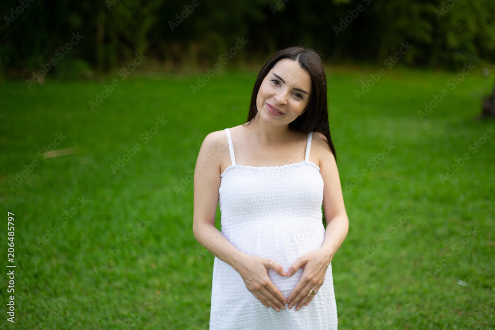 Pregnant couple walks in the park together holding hands Pregnant couple walks in the park together holding hands