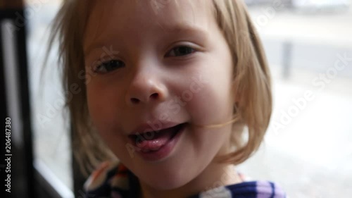 Cute grimace face portrait of a little child girl joyfully show tongue under air flow