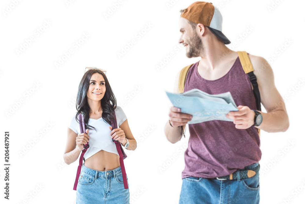 couple of young tourists with backpacks with map and walking together, isolated on white couple of young tourists with backpacks with map and walking together, isolated on white