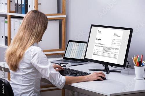 Businesswoman Checking Invoice On Computer