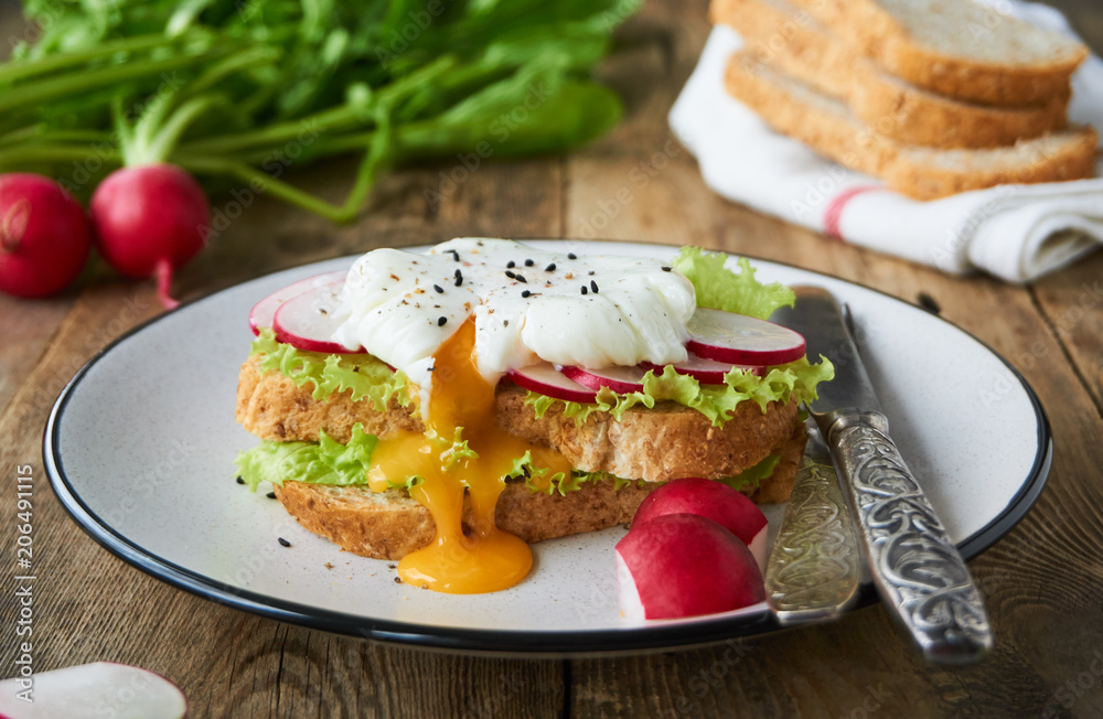 Sandwich with egg poached, radish and lettuce on a plate