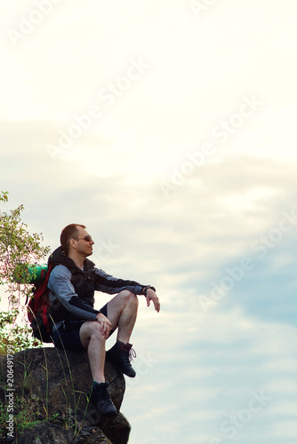 Hiker man with backpack sitting on top of mountain