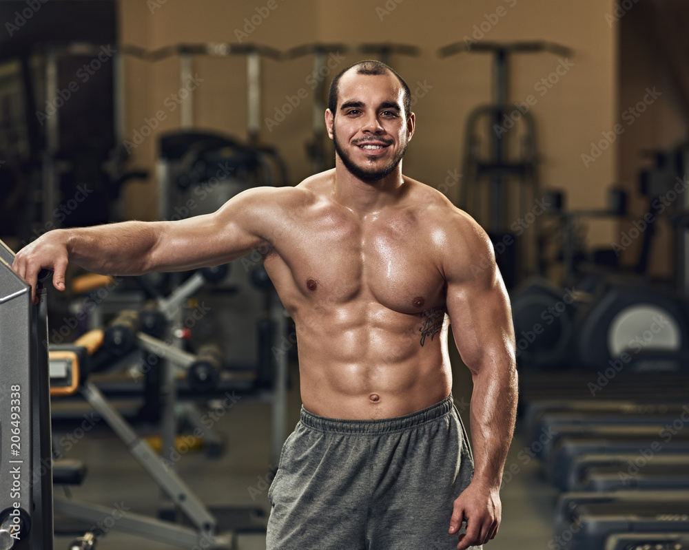 Fototapeta premium Smiling happy young athlete posing in modern gym