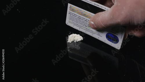 DRUGS: Man does a lines of heroin by plastic card - Close up. Plastic card and white powder. Lines and pile of cocaine on wooden table photo