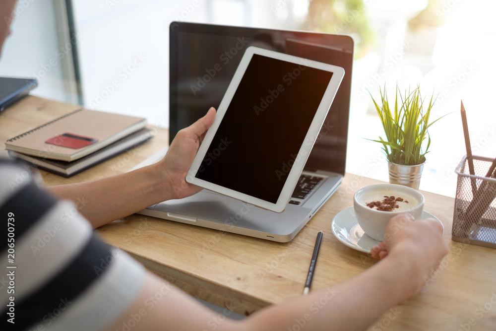 Closeup image of a man holding and using tablet with coffee cups on table in cafe Closeup image of a man holding and using tablet with coffee cups on table in cafe