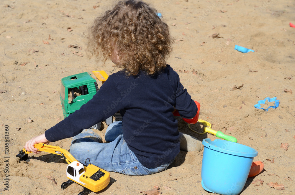 Kind spielt mit Spielzeug im Sandkasten Kind spielt mit Spielzeug im Sandkasten
