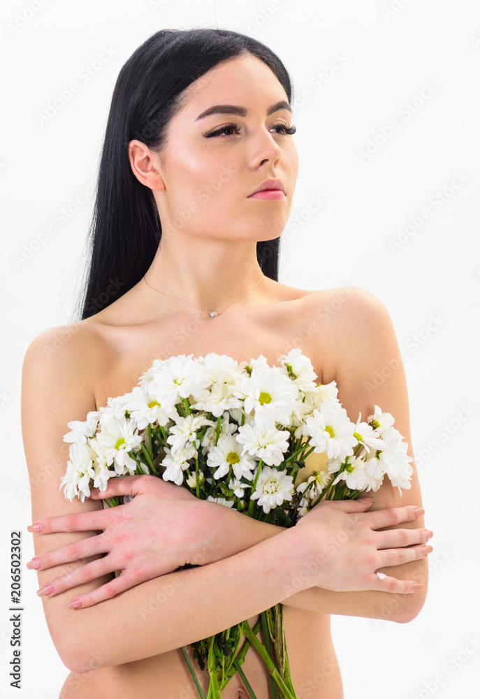 Woman with smooth healthy skin looks attractive. Lady covers breasts with flowers, isolated on white. Girl on calm face naked holds chamomile flowers in front of breasts. Natural cosmetics concept. Woman with smooth healthy skin looks attractive. Lady covers breasts with flowers, isolated on white. Girl on calm face naked holds chamomile flowers in front of breasts. Natural cosmetics concept.