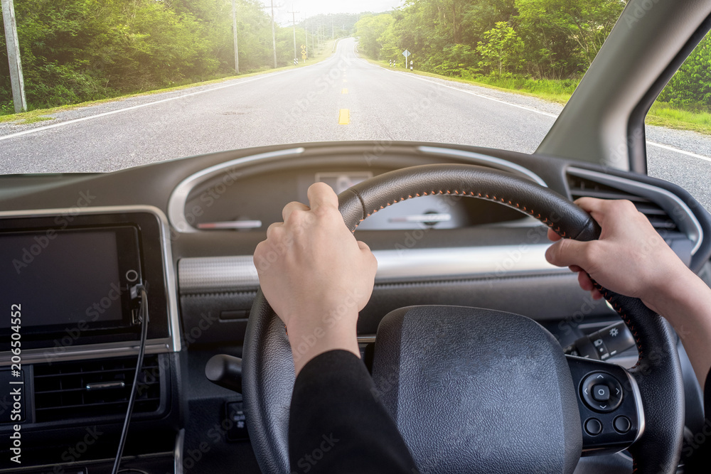 Hand holding right steering wheel with highway in rural Hand holding right steering wheel with highway in rural