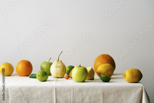 Citrus fruits, pear and apples on a table covered with linen tablecloth photo