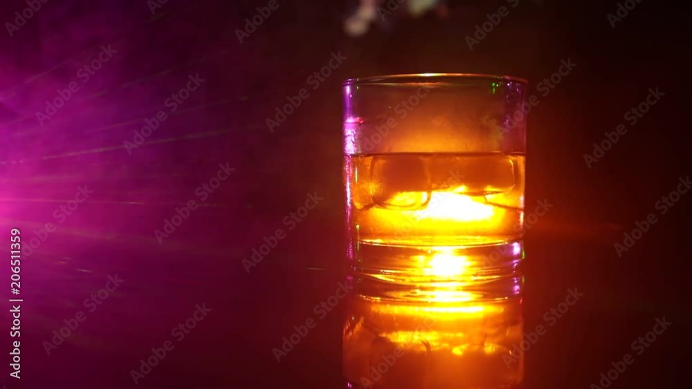Selective focus pure whisky with ice cube inside whisky glass on dark foggy background alcohol drink concept. Close up. Slider shot Selective focus pure whisky with ice cube inside whisky glass on dark foggy background alcohol drink concept. Close up. Slider shot
