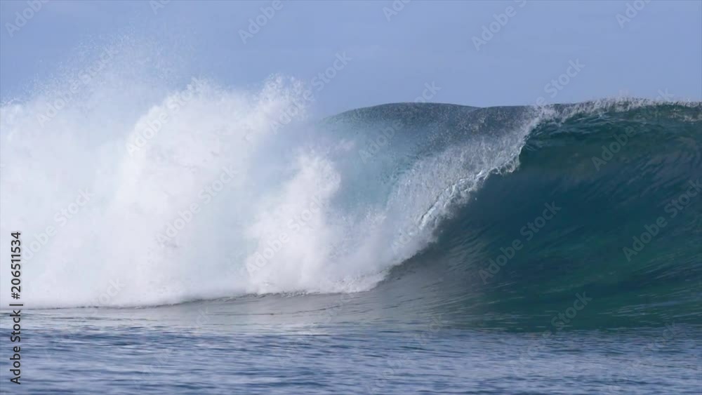 SLOW MOTION: Breathtaking deep blue barrel wave sparkles in the sun and rolls toward the tropical beaches. Spectacular shot of beautiful big ocean wave rushing over the reefs of the Pacific Ocean SLOW MOTION: Breathtaking deep blue barrel wave sparkles in the sun and rolls toward the tropical beaches. Spectacular shot of beautiful big ocean wave rushing over the reefs of the Pacific Ocean
