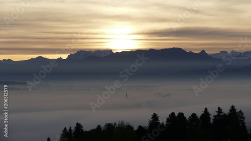 Sonnenaufgang mit Nebelmeer, Kirchturm und Berge ragen aus dem Nebel