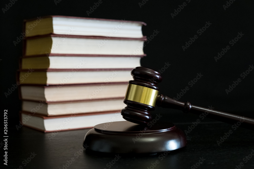 Judge gavel beside pile of books on wooden background Judge gavel beside pile of books on wooden background
