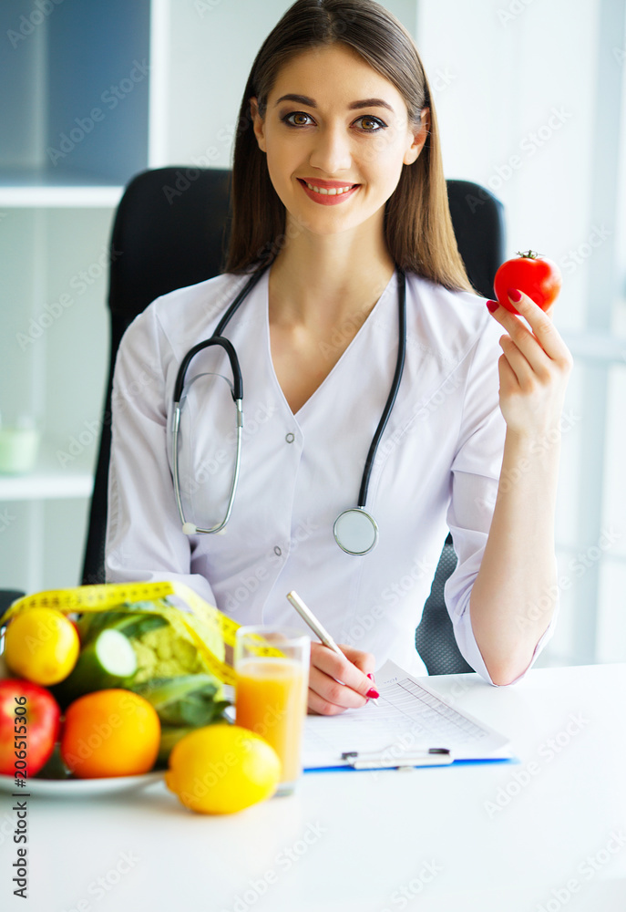 Health. Health Dietitian Sits At A Table With Fruits And Vegetables. The Doctor Draws up a Nutrition Plan. The Doctor smiles at Vibrating Happy and Holds in the Tomatoes Hands.High Resolution Health. Health Dietitian Sits At A Table With Fruits And Vegetables. The Doctor Draws up a Nutrition Plan. The Doctor smiles at Vibrating Happy and Holds in the Tomatoes Hands.High Resolution