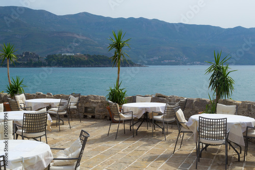 Tables and chairs of a street cafe without people near the sea. Montenegro. Budva