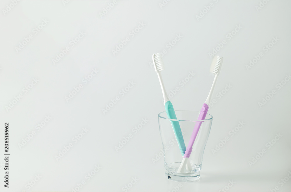 Green and purple toothbrush with transparent glass on white background Green and purple toothbrush with transparent glass on white background