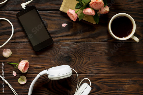 Smartphone, headphones, coffee cup on a wooden table. Top view flat lay background. Copy space.