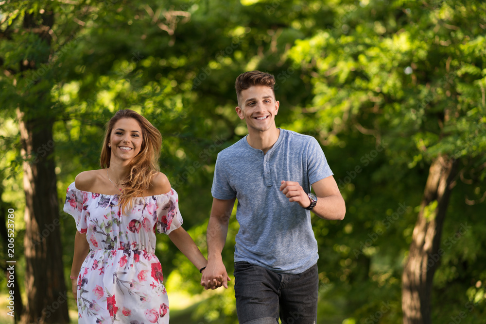 Happy couple holding hands and running in the  nature