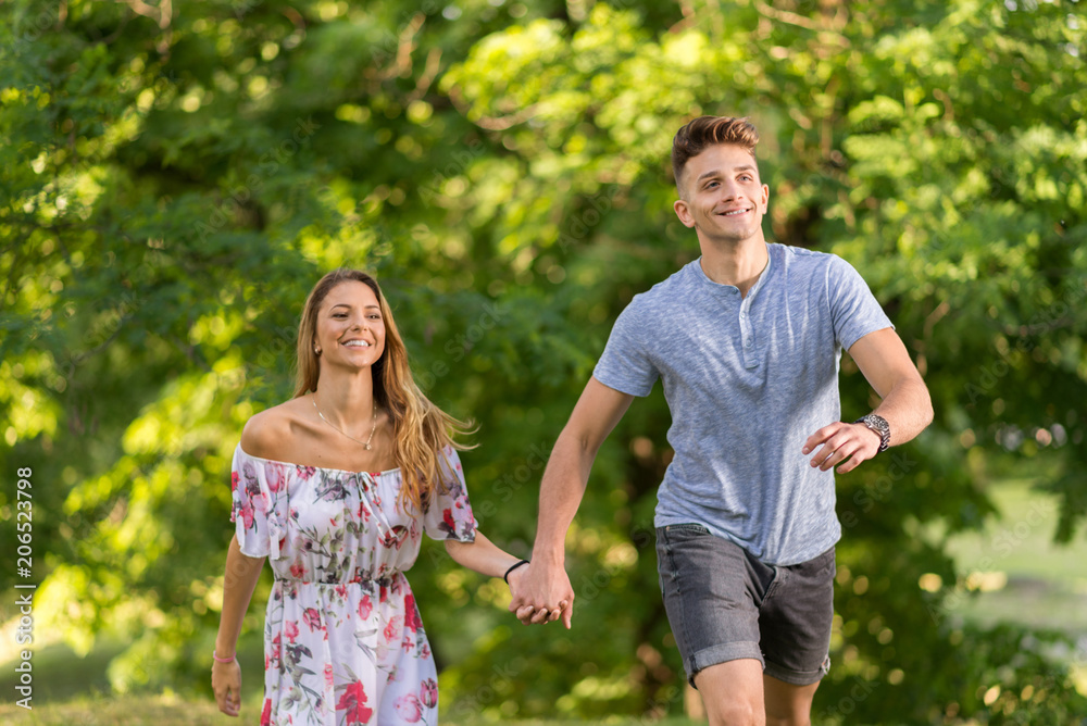 Happy couple holding hands and running in the nature Happy couple holding hands and running in the nature