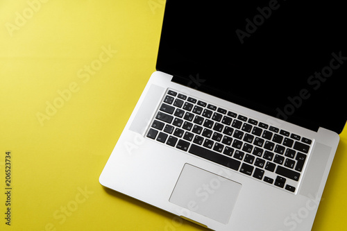 Flat lay with laptop on bright olive yellow background with copy space