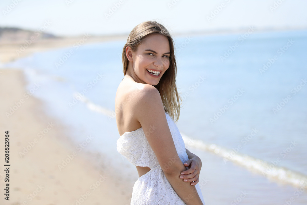 Junge blonde Frau steht lachend an einem Strand Junge blonde Frau steht lachend an einem Strand