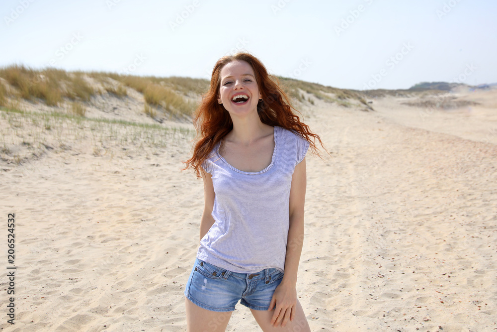Hübsche rothaarige Frau steht lachend an einem Strand Hübsche rothaarige Frau steht lachend an einem Strand