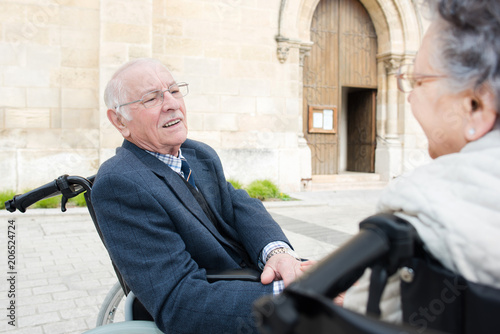 Elderly couple in wheelchairs outside of a church