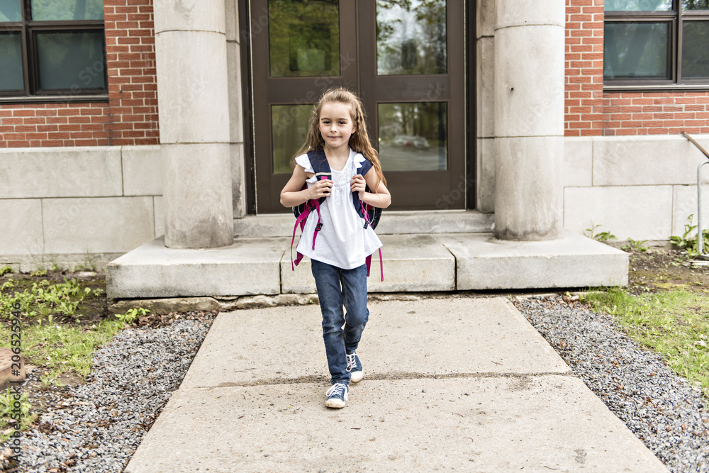 Portrait of cute girl with backpack outside of school