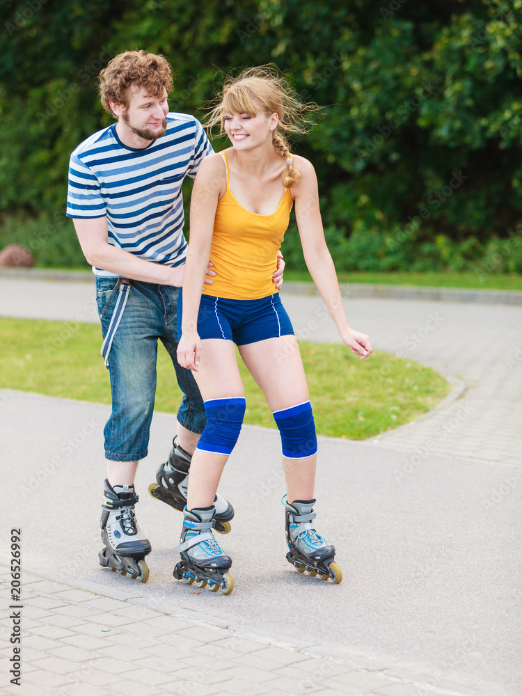 Young couple on roller skates riding outdoors Young couple on roller skates riding outdoors