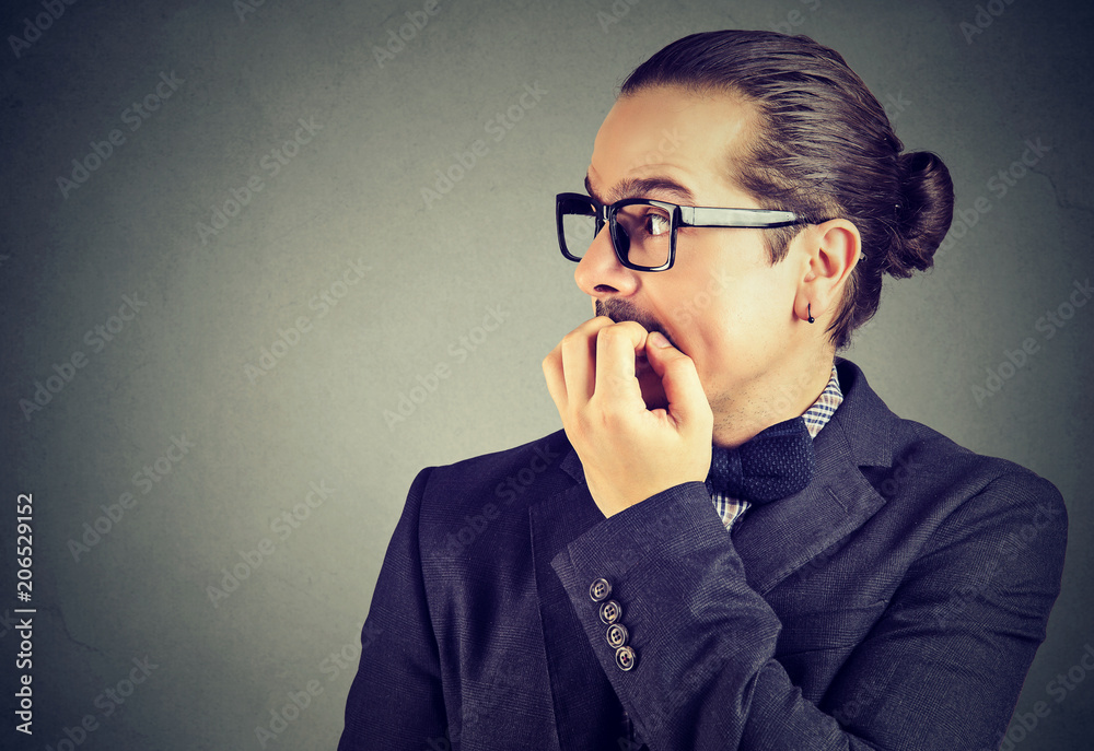 anxious young man biting his fingernails looking to the side anxious young man biting his fingernails looking to the side