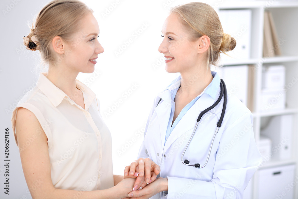 Blonde female doctor and patient talking in hospital office. Health care and client service in medicine Blonde female doctor and patient talking in hospital office. Health care and client service in medicine