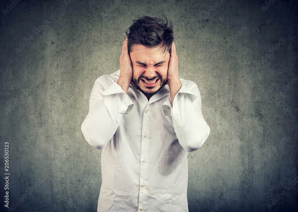 Frustrated man suffering with loud noise Frustrated man suffering with loud noise