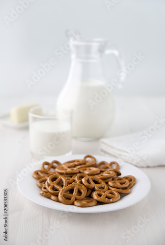 Crackers salted on a white plate with a glass jug of milk and a glass and cheese on a small plate. Selective focus. Blur