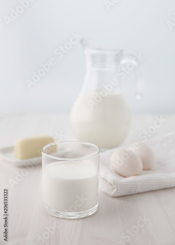A glass and a jug of milk with a piece of cheese and two eggs on a napkin. Selective focus. Blur