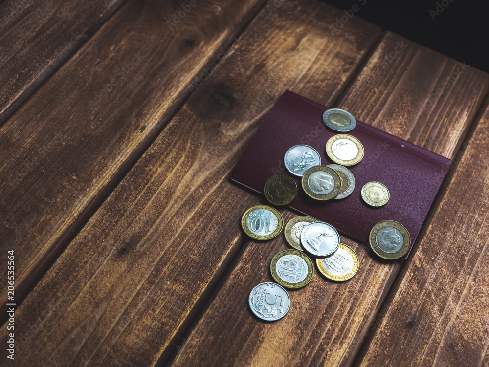 traveling, several international coins dropped on the passport on a wooden table traveling, several international coins dropped on the passport on a wooden table
