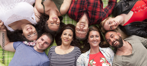 gruppenfoto von acht besten freunden kopf an kopf auf einer picknickdecke liegend.
