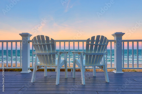 Fotografija Adirondack Chair sits on the balcony deck of a house looking out over the beach