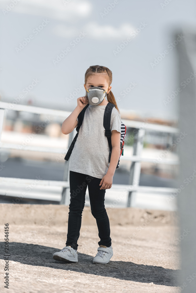Obraz premium child in protective mask walking to school on bridge, air pollution concept