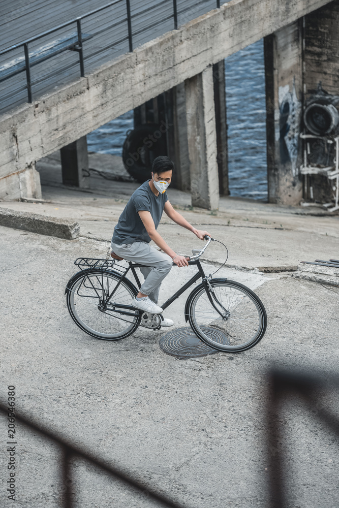 high angle view of asian teen in protective mask riding bicycle, air pollution concept